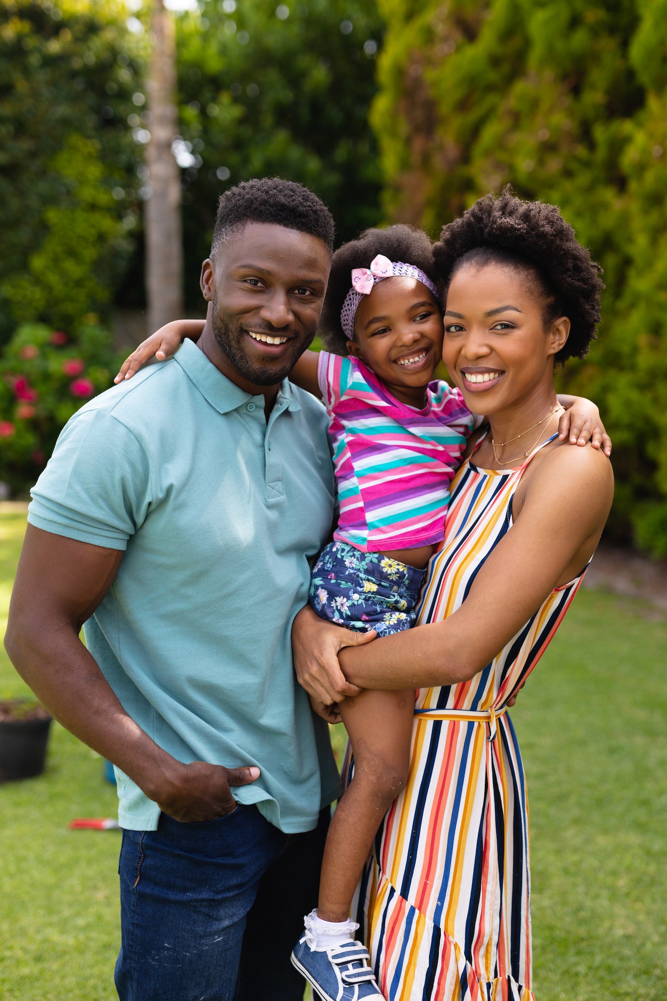 Portrait of smiling african american parents carrying daughter at garden